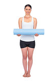 Cheerful slender model posing holding her rolled up mat
