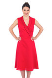 Smiling elegant brunette in red dress posing