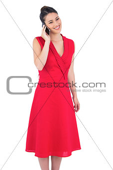 Smiling elegant brunette in red dress on the phone posing