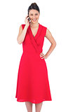 Cheerful elegant brunette in red dress on the phone posing