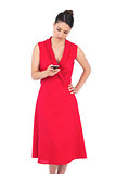Elegant brunette in red dress sending text message