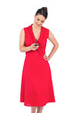 Smiling elegant brunette in red dress sending text message