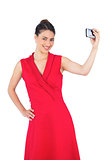 Happy elegant brunette in red dress taking picture