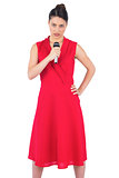 Serious elegant brunette in red dress singing
