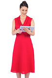 Content elegant brunette in red dress holding tablet pc