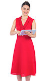 Smiling elegant brunette in red dress holding tablet pc