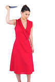 Angry elegant brunette in red dress holding knife