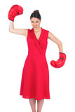 Angry gorgeous brunette in red dress wearing boxing gloves