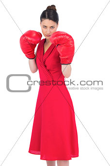 Elegant brunette in red dress wearing boxing gloves