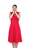 Excited elegant brunette in red dress posing