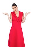 Hesitant elegant brunette in red dress posing