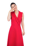 Glamorous model in red dress making phone call gesture