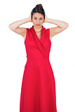 Glamorous young model in red dress covering her ears