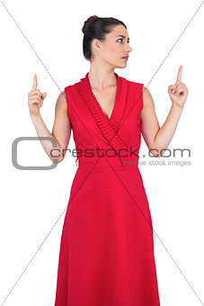Glamorous model in red dress pointing up