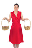 Cheerful glamorous model in red dress holding baskets