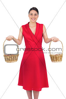Cheerful glamorous model in red dress holding baskets