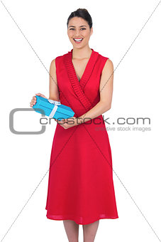 Smiling glamorous model in red dress holding present