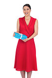 Happy glamorous model in red dress holding present