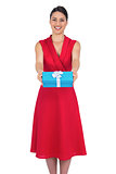 Happy glamorous model in red dress offering present