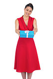 Smiling glamorous model in red dress offering present