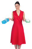 Smiling glamorous model in red dress holding presents