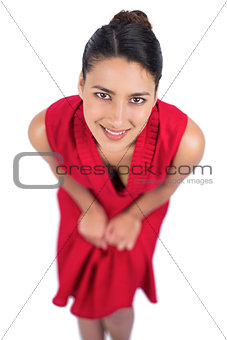 Smiling mysterious brunette in red dress posing