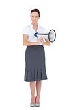 Unsmiling businesswoman holding megaphone