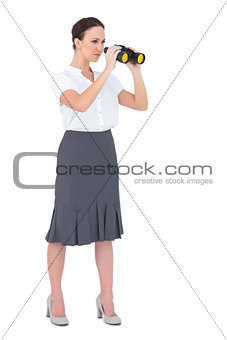 Serious elegant businesswoman looking through binoculars
