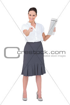 Stylish businesswoman pointing while holding newspaper