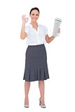 Stylish businesswoman making gesture while holding newspaper