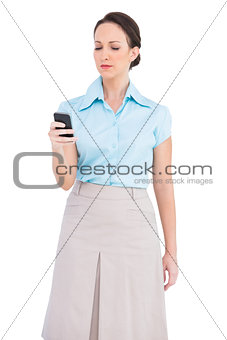 Serious classy young businesswoman sending text message