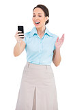 Cheerful classy businesswoman looking at her smartphone