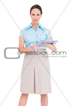 Serious young businesswoman holding tablet pc