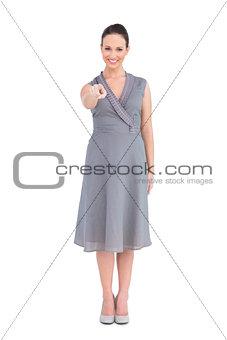 Elegant brunette in classy dress pointing at camera
