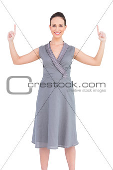 Happy elegant woman in classy dress pointing fingers up