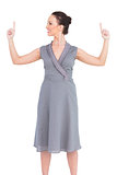 Cheerful elegant woman in classy dress pointing fingers up