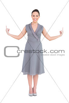 Happy gorgeous woman in classy dress pointing fingers up