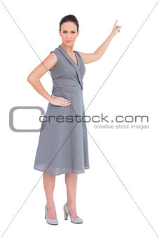 Frowning gorgeous woman in classy dress indicating direction