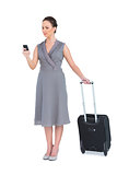 Serious gorgeous woman with her suitcase texting