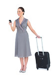 Smiling gorgeous woman with her suitcase texting