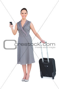 Cheerful gorgeous woman with her suitcase texting