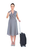 Cheerful gorgeous woman with her suitcase giving thumbs up