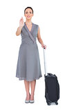 Cheerful gorgeous woman with her suitcase calling out to camera