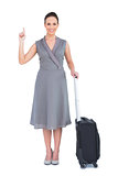 Cheerful gorgeous woman with her suitcase pointing her finger up