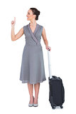 Cheerful gorgeous woman with suitcase pointing her finger up