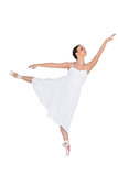 Focused ballet dancer posing on her tiptoe while rising a leg