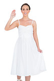 Smiling beautiful young model in white dress waving