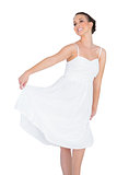Smiling beautiful young model in white dress dancing