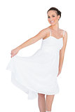 Cheerful beautiful young model in white dress dancing