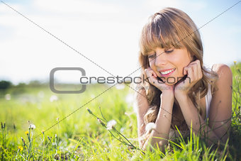 Smiling young woman on the grass looking at flowers